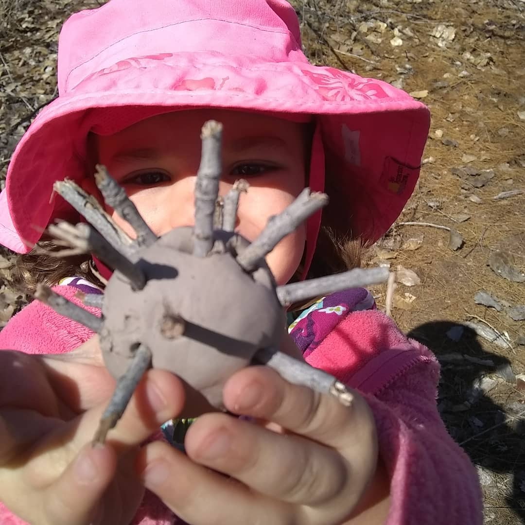 child holding up ball of clay with sticks